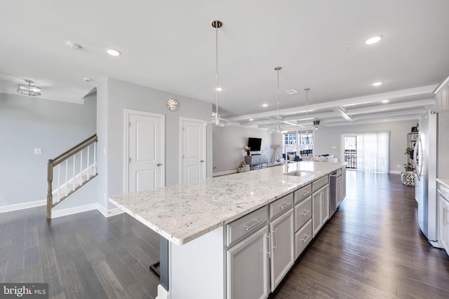 kitchen with dark wood-style floors, light stone countertops, a sink, a large island, and open floor plan