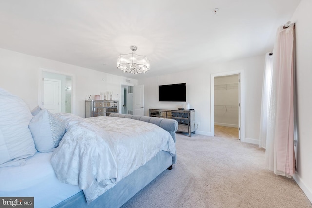 bedroom featuring an inviting chandelier, a spacious closet, baseboards, and light carpet