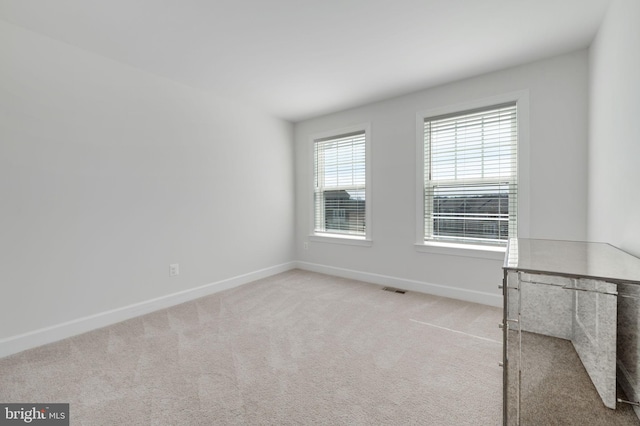 carpeted spare room with baseboards and visible vents