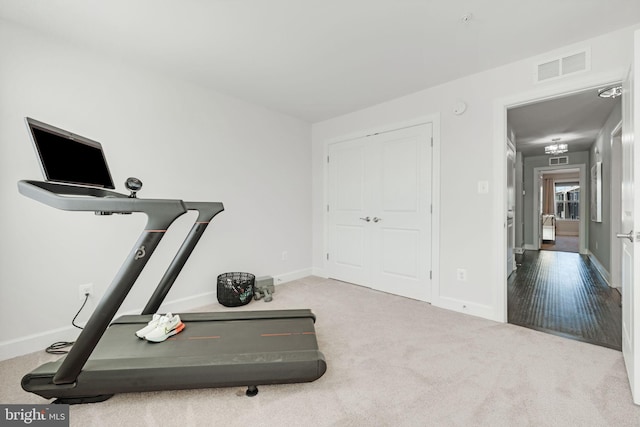 exercise area with visible vents, baseboards, and carpet