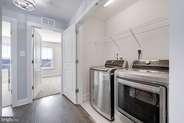 laundry area with visible vents, baseboards, washing machine and dryer, laundry area, and wood finished floors