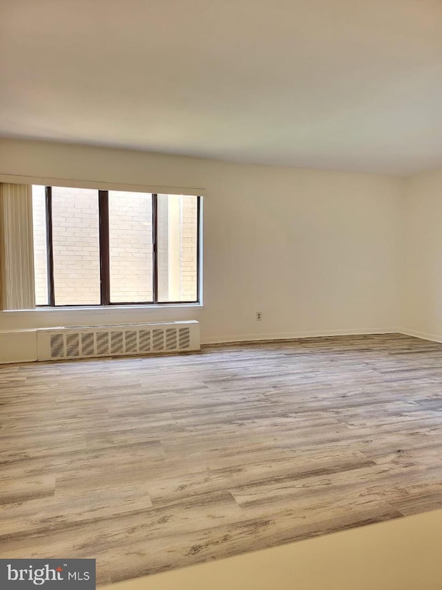 3100 S Manchester St Unit 909, Falls Church, VA 22044 - unfurnished room with baseboards, radiator heating unit, wood finished floors, and a healthy amount of sunlight