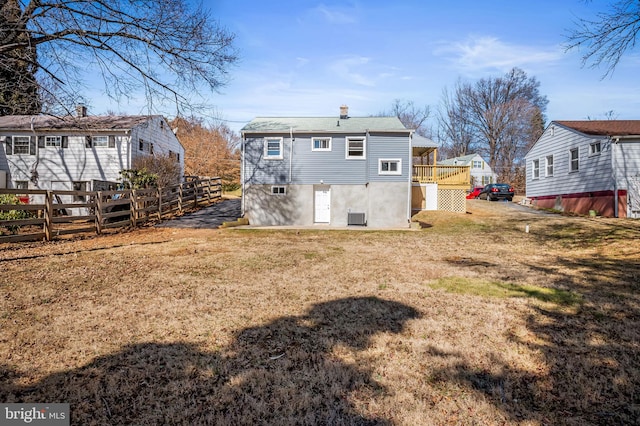 rear view of property featuring fence, a lawn, and a chimney