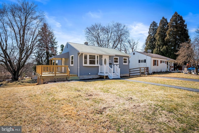 ranch-style house with a deck, a chimney, and a front yard