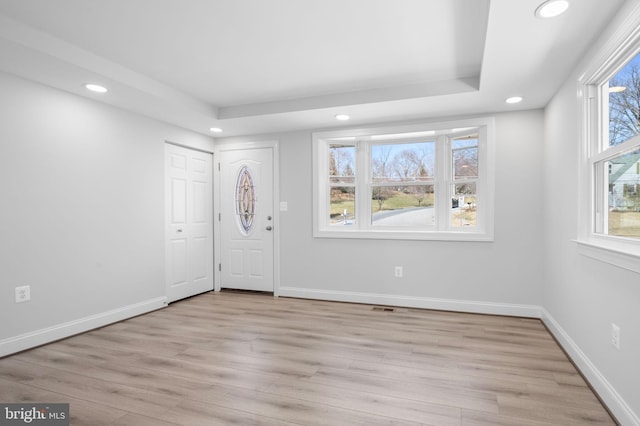 entryway featuring visible vents, baseboards, light wood finished floors, a tray ceiling, and recessed lighting