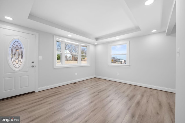 entryway featuring a raised ceiling, wood finished floors, and baseboards