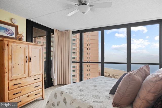 bedroom featuring light carpet, multiple windows, a textured ceiling, and a wall of windows