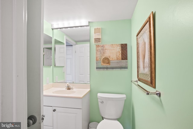 half bathroom featuring visible vents, toilet, and vanity