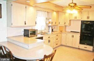 kitchen with a peninsula, a toaster, ceiling fan, light countertops, and dobule oven black