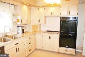 kitchen with a sink, stovetop, dobule oven black, and light countertops