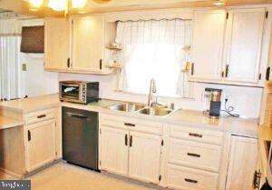 kitchen featuring a peninsula, a toaster, a sink, light countertops, and black dishwasher