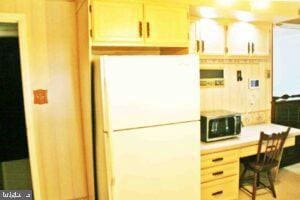 kitchen with stainless steel microwave, light countertops, freestanding refrigerator, and built in study area