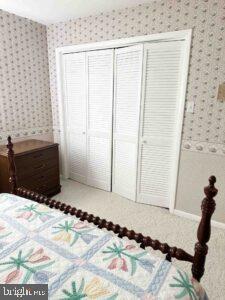 bedroom with a closet and wallpapered walls