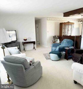 carpeted living room featuring beam ceiling