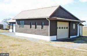 view of home's exterior featuring a standing seam roof, an outdoor structure, a detached garage, and metal roof