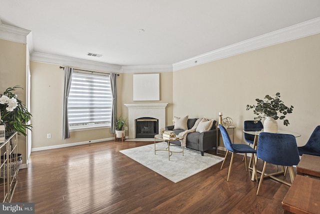 living room with visible vents, crown molding, a fireplace with flush hearth, and wood finished floors