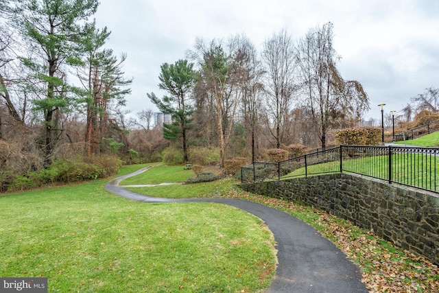 view of community with a yard, driveway, and fence