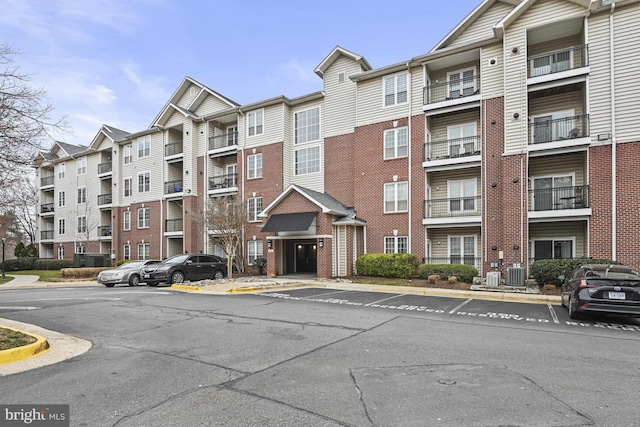 view of building exterior featuring central AC unit and uncovered parking