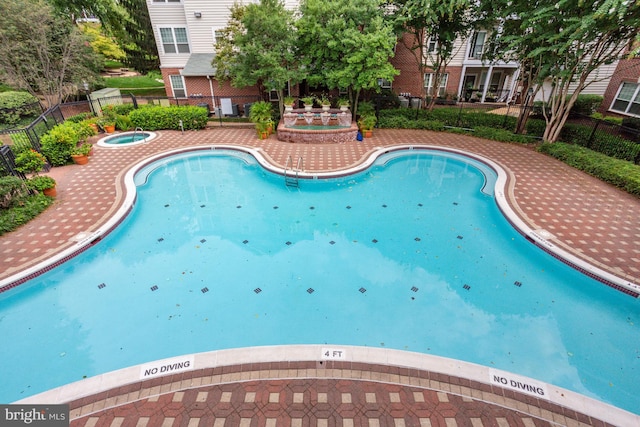 view of pool with fence and a hot tub