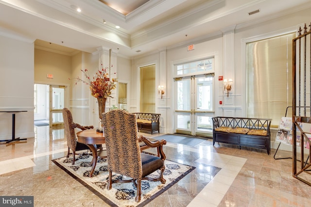 interior space with visible vents, a tray ceiling, a high ceiling, ornamental molding, and a decorative wall