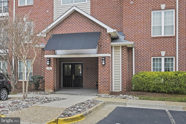 view of exterior entry with brick siding and uncovered parking