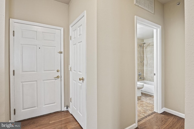 hallway with visible vents, baseboards, and wood finished floors