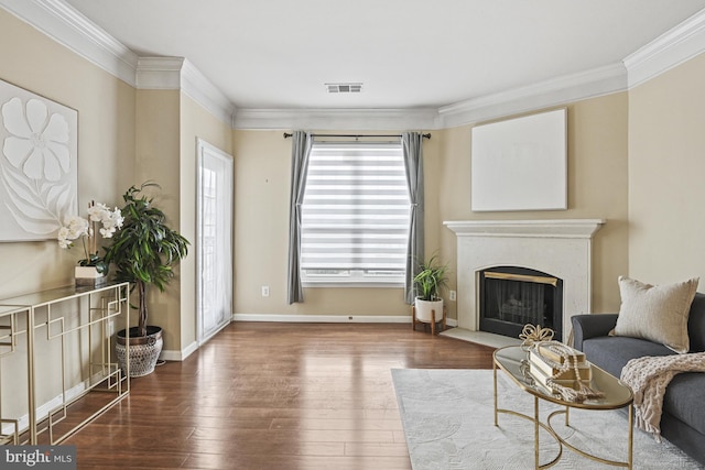 living area with visible vents, dark wood finished floors, crown molding, a premium fireplace, and baseboards