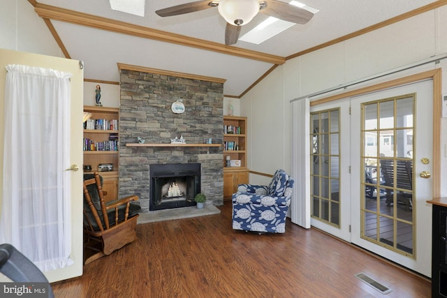 living area with wood finished floors, visible vents, vaulted ceiling with beams, a fireplace, and ornamental molding