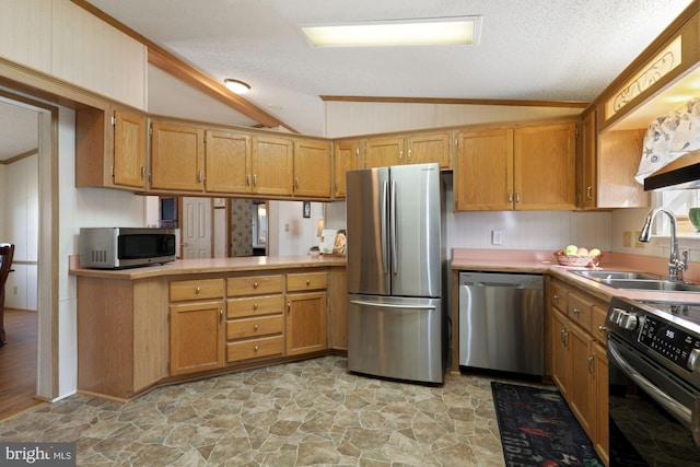 kitchen featuring a sink, vaulted ceiling, stone finish floor, light countertops, and appliances with stainless steel finishes