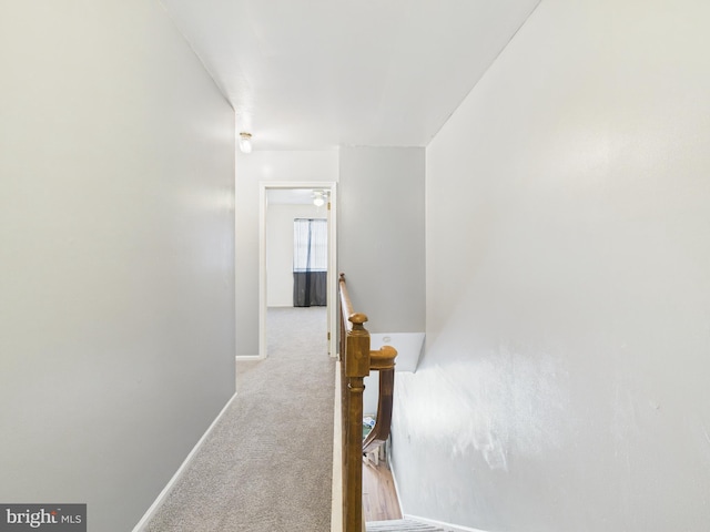 corridor featuring an upstairs landing, baseboards, and carpet floors