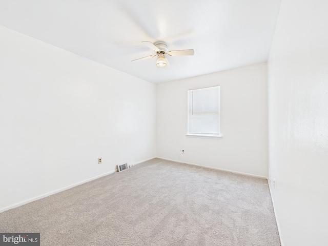 spare room with visible vents, light colored carpet, baseboards, and ceiling fan