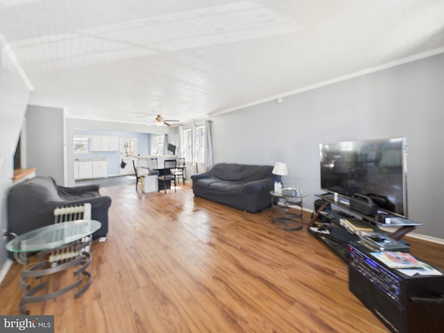 living room with a wealth of natural light, a ceiling fan, baseboards, and wood finished floors