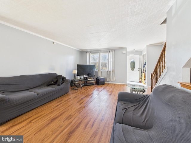 living room with ornamental molding, stairs, and hardwood / wood-style flooring