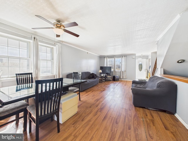 living room with a ceiling fan, wood finished floors, baseboards, and ornamental molding