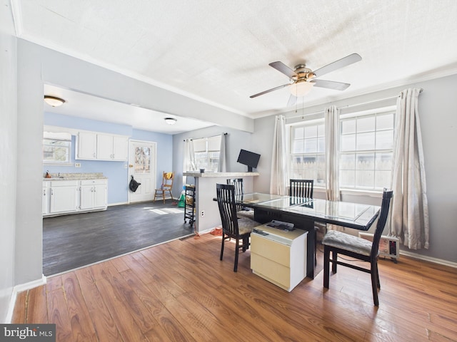 dining area with dark wood-type flooring, ornamental molding, a ceiling fan, a textured ceiling, and baseboards