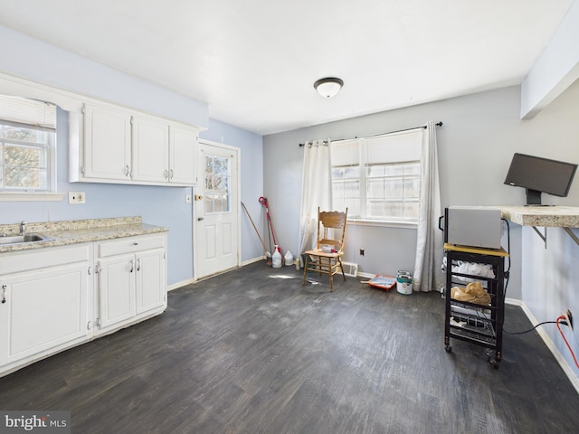 interior space with a sink, baseboards, dark wood finished floors, and white cabinetry