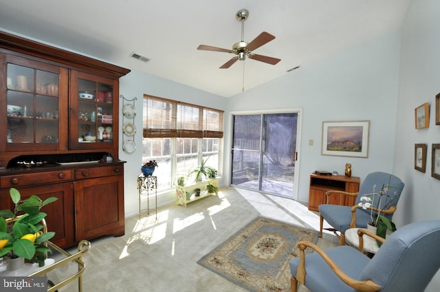 living area featuring visible vents, carpet flooring, ceiling fan, and vaulted ceiling