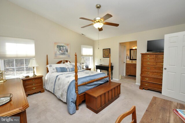 bedroom featuring multiple windows, light colored carpet, ensuite bath, and vaulted ceiling