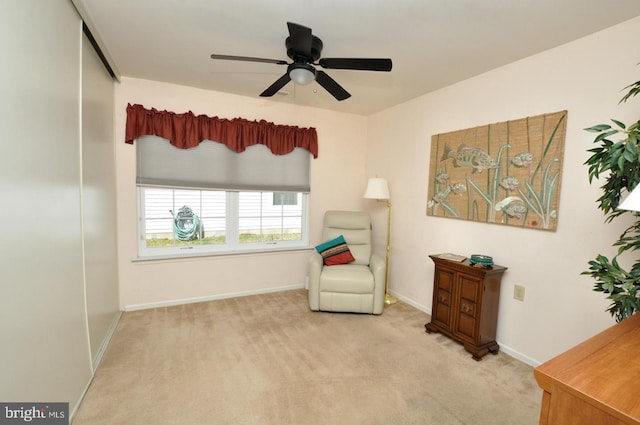 sitting room featuring carpet flooring, baseboards, and ceiling fan