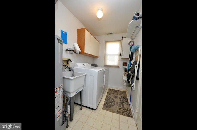 clothes washing area featuring visible vents, washer and dryer, water heater, cabinet space, and light tile patterned floors