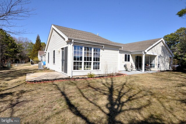 rear view of house featuring a yard, central air condition unit, a shingled roof, and a patio area