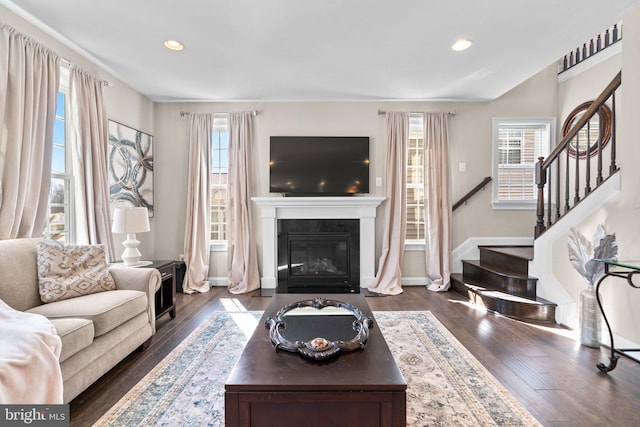 living room featuring recessed lighting, stairway, a glass covered fireplace, and dark wood-style flooring