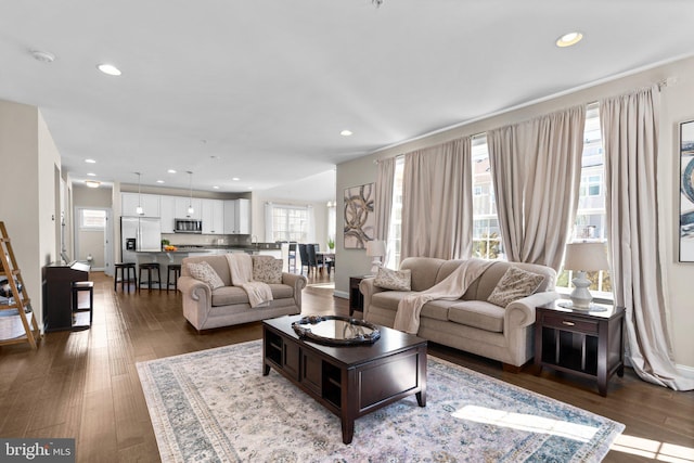 living area with dark wood-type flooring and recessed lighting