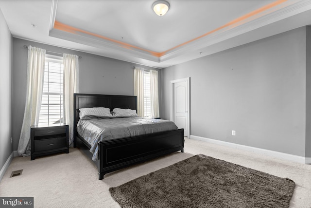 bedroom featuring carpet flooring, multiple windows, and a raised ceiling