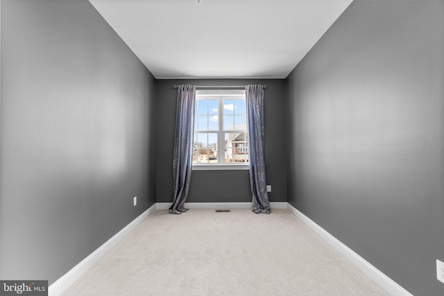 spare room with light colored carpet and baseboards