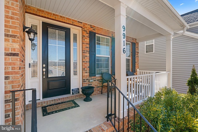 property entrance with covered porch and brick siding