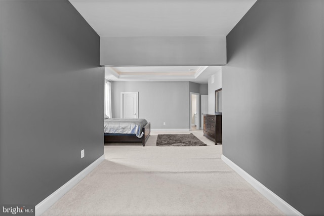 carpeted bedroom featuring a tray ceiling and baseboards