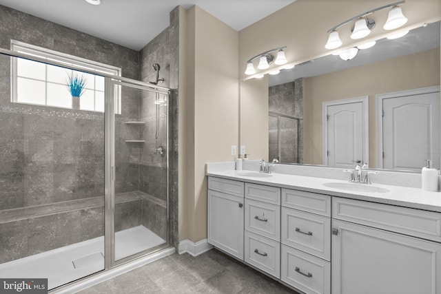 bathroom featuring double vanity, a stall shower, baseboards, and a sink