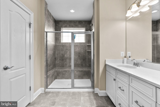 full bathroom featuring vanity, baseboards, and a stall shower