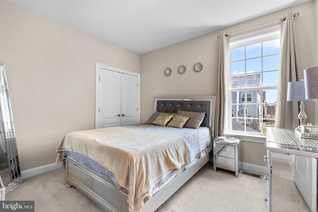 bedroom featuring a closet, carpet flooring, visible vents, and baseboards